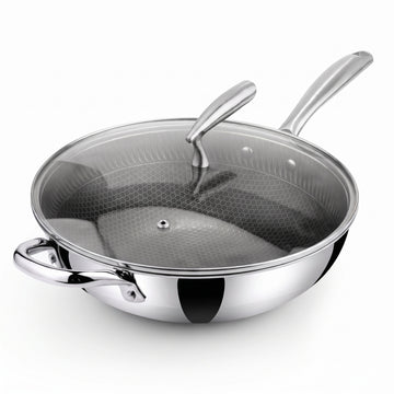 A stainless steel Zinox Clad wok with a weighted glass lid that has a steam vent and an ergonomic stainless steel handle, the wok has a honeycomb textured non-stick ceramic interior and two polished stainless steel handles one long handle and one helper handle on the other side, both handles are riveted to the wok's body. the product is shown on a clean white background.