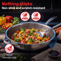 A Zinox Clad stainless steel wok filled with colorful stir-fried vegetables, shown on a dark kitchen-style background with promotional text reading 'Nothing sticks Non-stick and scratch resistant' and icons for PTFE and PFAS free, and metal utensils safe.